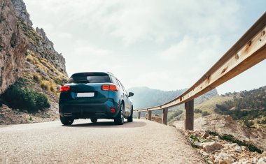 Dağ yolundaki asfalt yolda hızlı hareket eden kompakt otomobil çelik trafik korkuluklarıyla. İspanya 'daki Mallorca adasında seyahat etmek, araba kiralamak ya da yol konsepti imajında güvenlik.