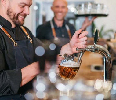 İki erkek arkadaş barmen ve garson tepside siyah üniforma giyip birbirlerine gülümsüyorlar. Samimi insanlar ilişkileri, takım çalışması, erkekler arkadaşlık ve iyi ruh hali imajı..