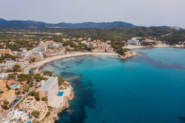 Beautiful aerial drone view shot of Peguera town on rocky Mediterranean cliff coast with cozy tranquil turquoise bays washed with sea waves. Traveling and Balearic Islands vacation concept clipart