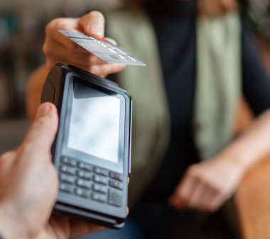 Kablosuz banka ödemesi yapan genç bir kadın POS terminal işlemleri ile birlikte kapalı kafeterya restoranından satın alınıyor. Makineye odaklan. Finans, restoran endüstrisi, küçük işletmeler.