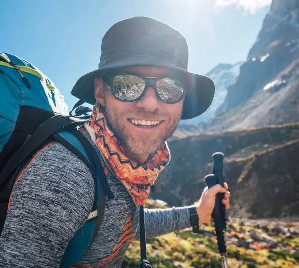 ポートレートヤングハイカーバックパッカーマンは高高度化歩行中にマカルバランパークルートのカメラで笑顔でサングラスで男 ピーク トレッキング ルート ネパール アクティブバケーションコンセプトイメージ ストックフォト