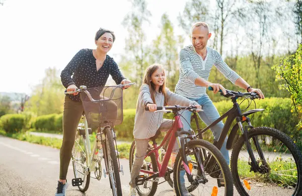 夏の屋外自転車に乗っている間 娘と一緒に笑顔の父と母 彼らは夏の都市公園で一緒に楽しむ 幸せな親と子供時代やアクティブなスポーツライフコンセプトイメージ ストック写真