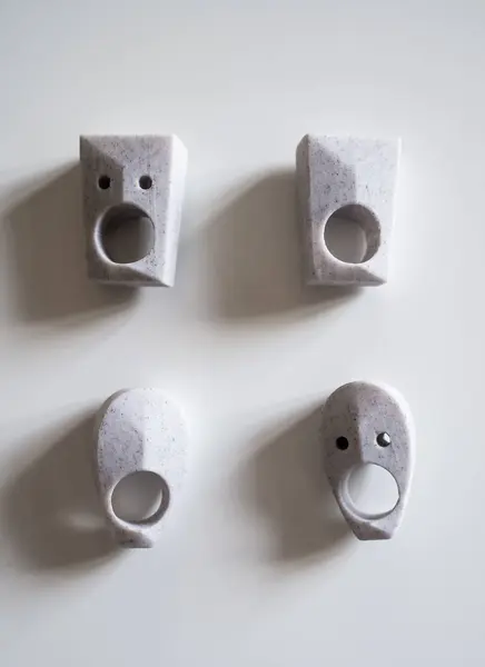 stock image Four modern art stone finger rings featuring unique abstract face design with large circular opening, two small holes for eyes.Rings vary between angular rounded shapes showcasing minimalist aesthetic