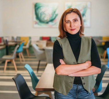 Küçük işletme sahibi gibi gülümseyen, restoran salonunda şef üniforması giymiş bir kadının portresi. Başarılı insanlar, sıkı çalışma, tüketici, kafe, restoran endüstrisi konsepti.