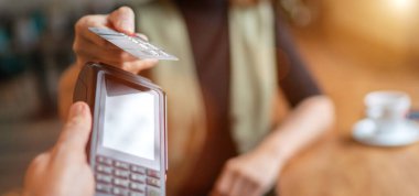 Kablosuz banka ödemesi yapan genç bir kadın POS terminal işlemleri ile birlikte kapalı kafeterya restoranından satın alınıyor. Makineye odaklan. Finans, restoran endüstrisi, küçük işletmeler.