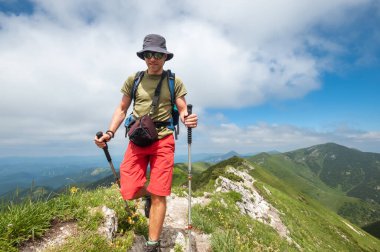 Yürüyüş direkleriyle gezen gezgin, sırt çantalı gezgin güneşli bir günde kayalık dağ yolunda gezinen manzaralı arka planda açık hava macerasının özünü yakalayan yeşil tepeler, keşif. Mala Fatra Slovakya.