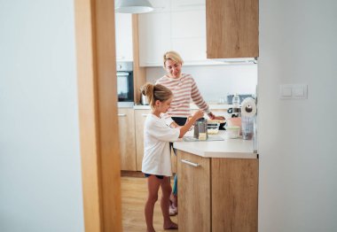 Anne ve kızı, modern mutfakta birlikte yemek pişirmekten, birlikte vakit geçirmekten ve yemek hazırlığında kaynaşmaktan hoşlanırlar. Anne ve çocuk ilişkileri ve güzel ev imajı..
