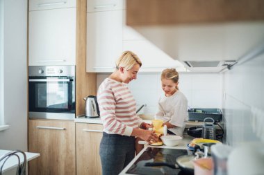 Anne ve kızı, modern mutfakta birlikte yemek pişirmekten, birlikte vakit geçirmekten ve yemek hazırlığında kaynaşmaktan hoşlanırlar. Anne ve çocuk ilişkileri ve güzel ev imajı..