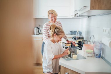 Anne ve kızı, modern mutfakta birlikte yemek pişirmekten, birlikte vakit geçirmekten ve yemek hazırlığında kaynaşmaktan hoşlanırlar. Anne ve çocuk ilişkileri ve güzel ev imajı..