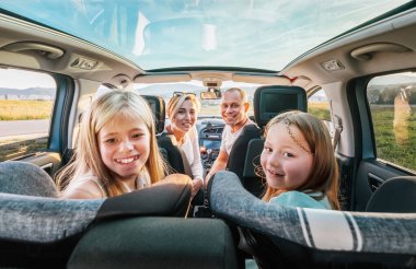 Çatı şeffaflığı olan modern bir arabada oturan kızları olan genç bir çift. Mutlu aile anları, çocukluk, fast food yemek ya da otomobil yolculuğu öğle yemeği arası konsepti imajı.