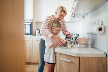Anne ve kızı Gratering peyniri, mutfakta birlikte yemek pişirmekten, birlikte vakit geçirmekten ve yemek hazırlığında kaynaşmaktan zevk alır. Ebeveyn ve çocuk ilişkileri ve güzel ev konsepti imajı