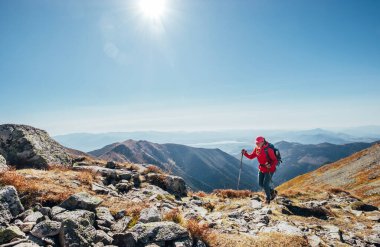 Sırt çantalı, parlak kırmızı ceketli bir kadın, batı Tatras, Slovakya 'da Liptov vadisi arka planında yürüyüş direkleri kullanıyor. Aktif insanlar ve Avrupa yürüyüş konsepti imajı.