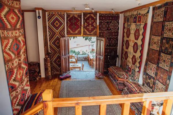 Konforlu Türk halı dükkanı, karmaşık geometrik desenli geleneksel el yapımı halılardan oluşan canlı bir koleksiyon sergiliyor. Ilık ahşap iç döşeme, zengin kültürel deneyimleri davet eden renkli görüntüyü geliştirir.
