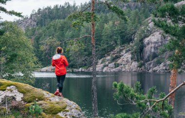 Genç turist kadın Norveç 'in Telemark bölgesinde Norveç' in vahşi gölünün tadını çıkarıyor. İskandinav ülkelerinde seyahat etmek konsept imajı.