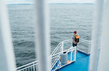 Sırt çantalı bir kadın İsveç 'ten gelirken Norveç feribotunda Kuzey Denizi manzarasının tadını çıkarıyor. Sahne, rahatlamış seyahatin özünü yakalar. Manzaralı Baltık deniz manzaralarını inceler..