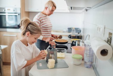 Anne ve kızı, modern mutfakta birlikte yemek pişirmekten, birlikte vakit geçirmekten ve yemek hazırlığında kaynaşmaktan hoşlanırlar. Anne ve çocuk ilişkileri ve güzel ev imajı..