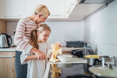 Anne ve kızı, modern mutfakta birlikte yemek pişirmekten, birlikte vakit geçirmekten ve yemek hazırlığında kaynaşmaktan hoşlanırlar. Anne ve çocuk ilişkileri ve güzel ev imajı..