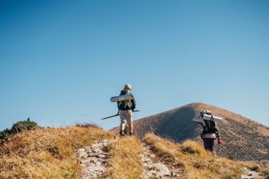 Sırt çantaları ve izleme direkleriyle Slovak Mala Fatra dağ sırasının yanından geçen annesiyle gezen bir çocuk. Vahşi doğada aktif yaşam tarzı ve aile ilişkileri kavramı