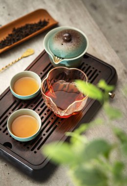 Seramik Gaiwan 'ın natürmort fotoğrafı, cam sürahi, çay fincanları seremoni odasında taze demlenmiş koyu oolong çayı. Yumuşak ışık, sakin düşünceli Çin geleneğini çağrıştırıyor.. 