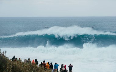Uluslararası sörfçüler Praia do Norte 'de Nazare, Farol da Nazar, Portekiz' de büyük Atlantik okyanus dalgalarının tadını çıkaran insanlar en yüksek sörf rekorunun kırıldığı yerde
