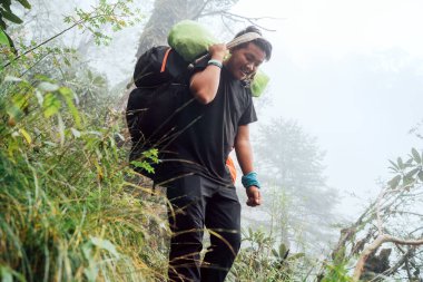 Kapıcı olarak çalışan güçlü bir Şerpa adamının portresi. Alnında geleneksel bir metot taşıyan büyük bir kargo taşıyor. Mera zirvesi tırmanışı sırasında yüksek Himalayalar seferi. Ulaşım veya mal teslimatı kavramı