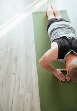 Oturma odasında antrenman yapıyorum. Genç kaslı vücut adamının elmas şınav çekişini en iyi gören yer. Sağlıklı yaşam tarzı ve modern çevrimiçi teknoloji kavramı.