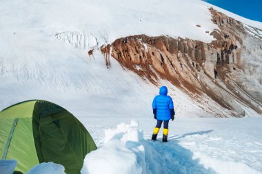 Yalnız dağcı kadın yüksek dağcılık kıyafetleriyle Kazbek 5054 metre dağının keyfini çıkarıyor ileri kamp alanı, Kafkasya, Gürcistan