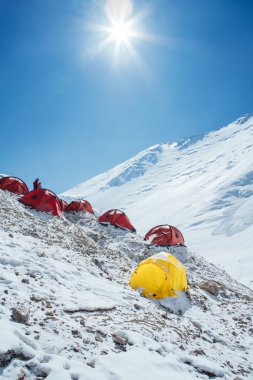 Kamp 2, 5300 metrede. Karlı Lenin Buzulu 'nda Pamir dağlarının geniş güneşli panoramik manzaralı parlak çadırları vardır. Aktif insanlar konsepti. Kırgızistan, Orta Asya 'da Lenin zirvesi rotası.