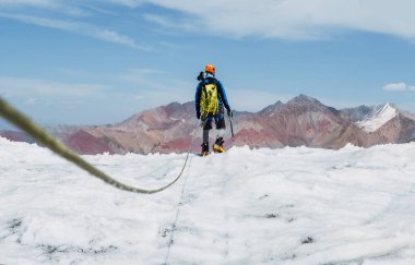 Halat takımının dağcılık teçhizatının arka görüntüsü. Lenin zirvesi açık gökyüzünün altında, arka planda dağ zirveleriyle birlikte buzul üzerinde tırmanış yapıyor. Aşırı aktif insanlar, yüksek irtifa dağcılık konsepti