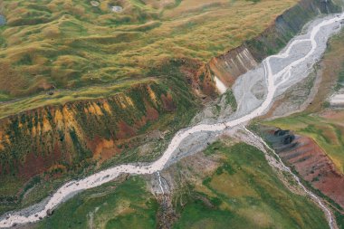 Dağ nehrinin inanılmaz bir görüntüsü. Pamir dağlarının derinliklerindeki yeşil tepelerin etrafını kollar sarmış. Lenin zirvesi, 3600 metre yakınındaki Kırgızistan, Orta Asya 'daki Merkez Kamp' a alışma rotası.