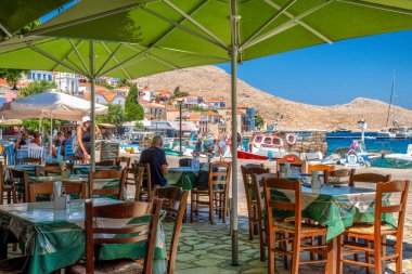 Halki, Yunanistan - 6 Temmuz 2022: Yunanistan 'ın Halki (Chalki) adasında deniz manzaralı Yunan tavernası