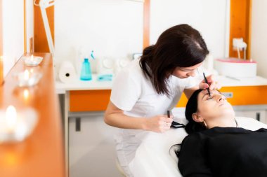 Güzellik uzmanı güzellik salonunda kirpik uzatma prosedürü uyguluyor. Kalıcı kirpikleri var.