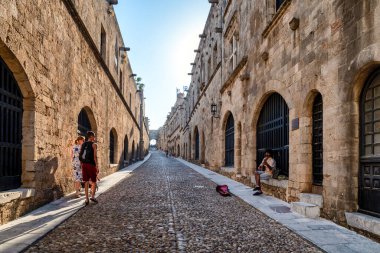 RHODES, GREECE - 4 Temmuz 2022: Yunanistan 'ın Rodos kentindeki Old Town' daki Street of the Knights 'da gitar çalan sokak sanatçısı