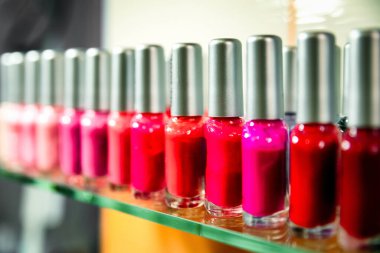 Tırnak cilası şişeleri kırmızı gölgeler ve mor tonlarla sıraya dizilir.