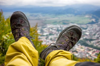 Yürüyüş botlu turist bacakları. Şehrin tepenin altından manzarayı izle. Yazın açık hava aktiviteleri