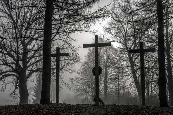 Wooden chrisrtian crosses in dark  foggy autumn park with trees.