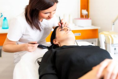 Güzellik uzmanı güzellik salonunda kirpik uzatma prosedürü uyguluyor. Kalıcı kirpikleri var.