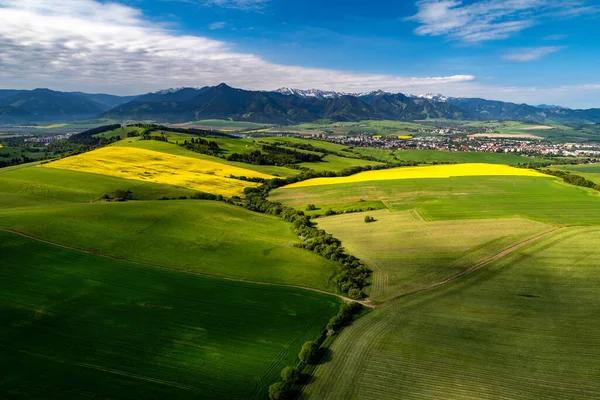 Beautiful country landscape with green, yellow fields and city Liptovsky Mikulas, Low Tatras mountains at background. Liptov, Slovakia.  Aerial drone photography