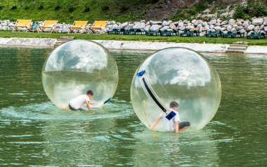 Ruzomberok, Slovakya - 23 Ağustos 2015: Aquazorbing. Hrabovo tatil köyündeki gölde çocuklar eğleniyor.