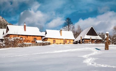 VLKOLINEC, SLOVAKIA - JANUARY 31, 2015:  Wooden cottagec covered by snow in village Vlkolinec, Slovakia clipart