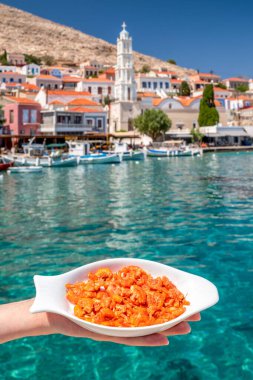 Halki, Yunanistan - 6 Temmuz 2022: Halki adasında arka planda kırmızı karides ve mavi deniz tabağı