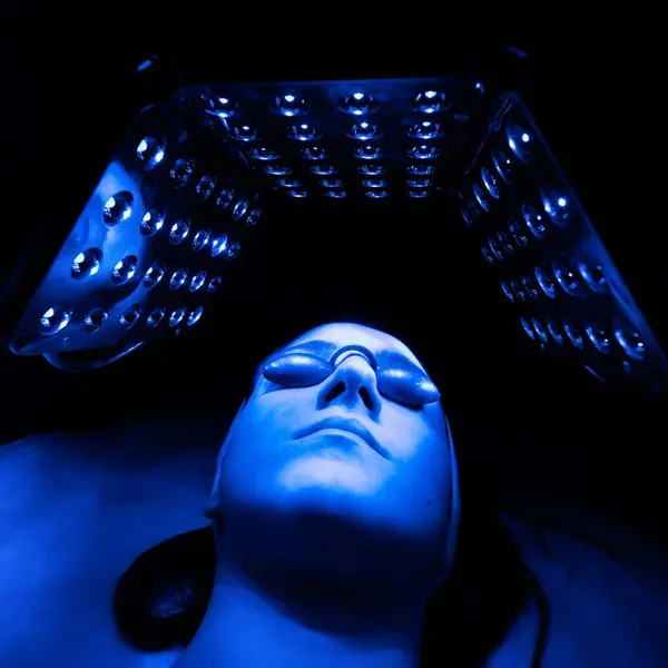 stock image Young woman having LED light facial treatment in beauty salon.