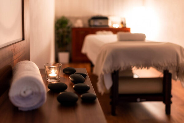 Towel, candle and lava stones in spa salon. Bluerred. massage table in the background