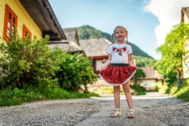Kırsal kesimde geleneksel Vlkolinec köyünde, Slovakya 'da ahşap kulübelerle poz veren dört yaşında mutlu küçük bir kız çocuğu.