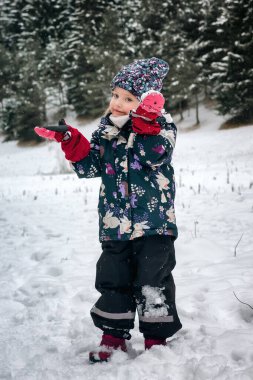 Mutlu küçük kız doğada karla oynuyor..