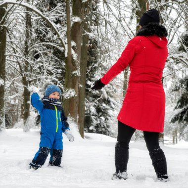 Anne ve bebek karlı kış ormanlarında oynuyorlar..