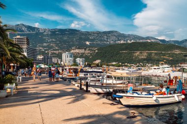 Budva, Karadağ - 24 Ağustos 2023: Karadağ 'daki Budva tatil beldesinde limanda teknelerin yakınında yürüyen insanlar