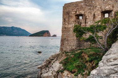 Budva 'nın eski kasabasındaki Hisar duvarları. Arkaplanda Sveti Nicola Adası.