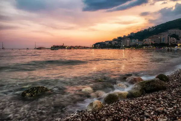 Budva, Karadağ - 24 Ağustos 2023: Karadağ 'daki Budva tatil beldesinde gün batımında çakıl taşı plajı