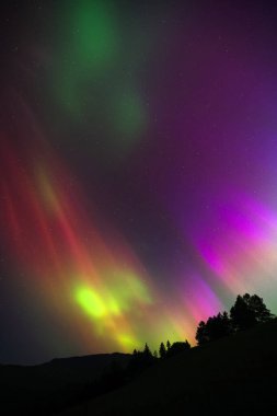 Aurora Borealis, dağların siluetiyle Kuzey Işıkları.